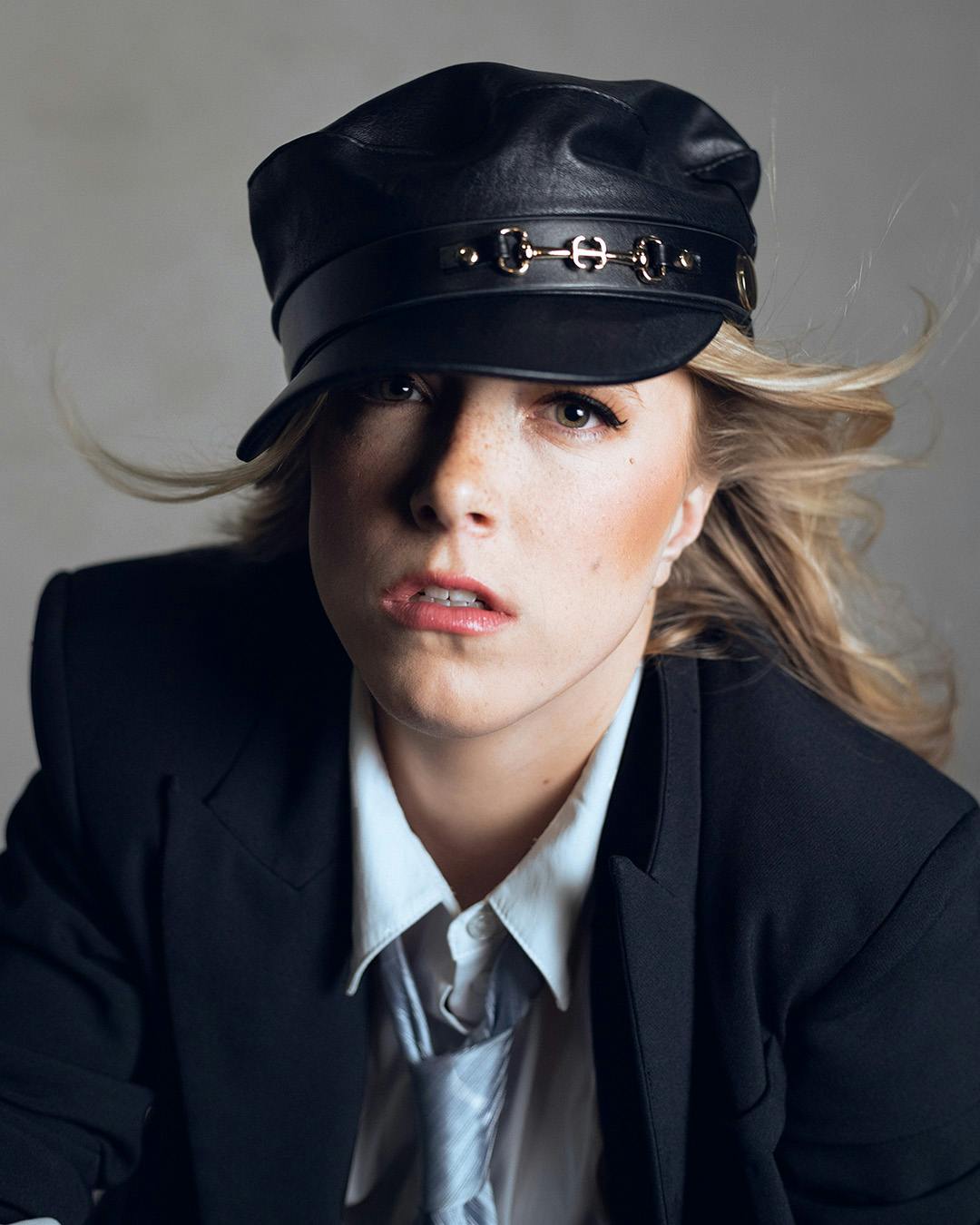 Girl wearing black hat and outfit in low-key lighting.