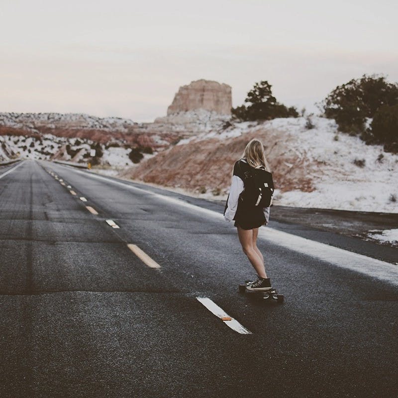 Girl skateboarding down empty street.