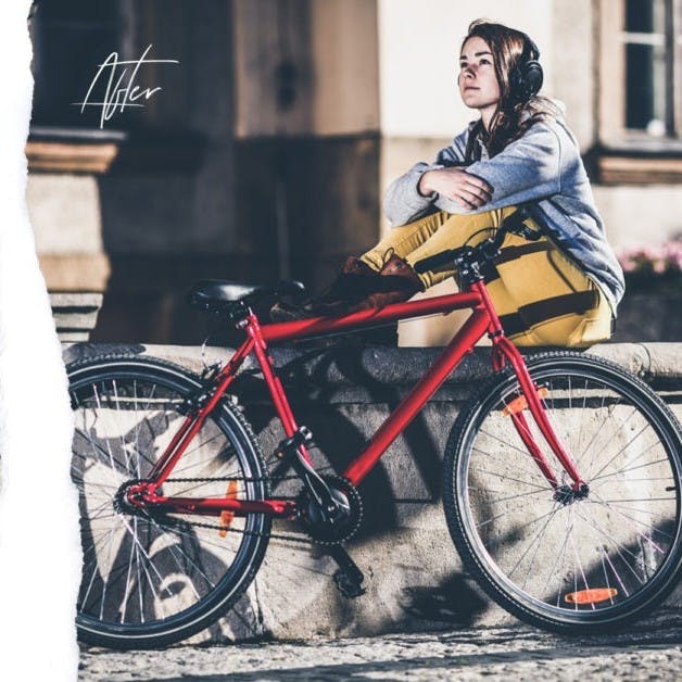 Girl standing near red bike.