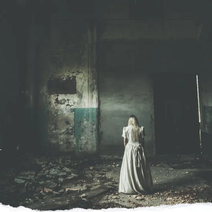 Woman in white dress standing in abandoned building.
