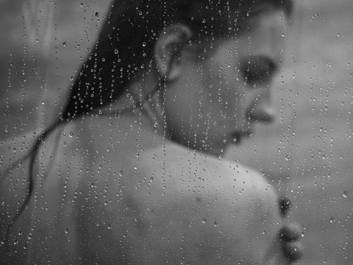 Boudoir photo of a woman behind glass with water on it.