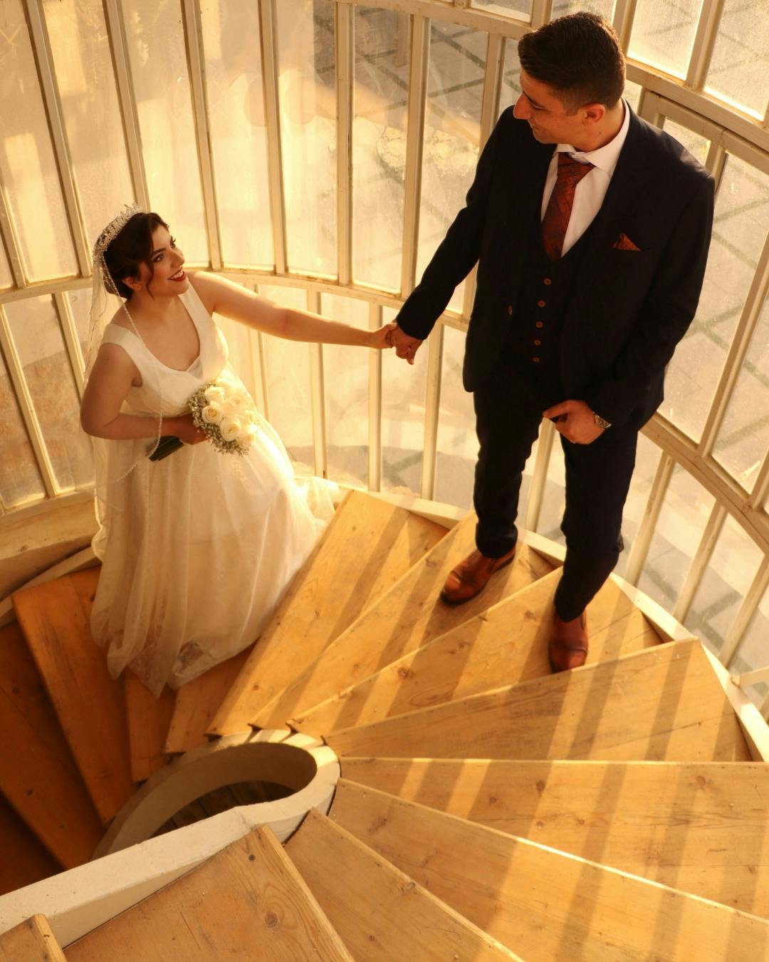 Woman walking with groom up curved leading line staircase.