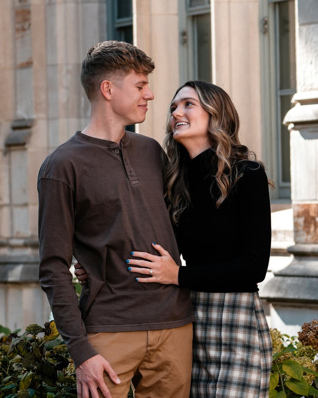 Example engagement portrait of couple in front of building.