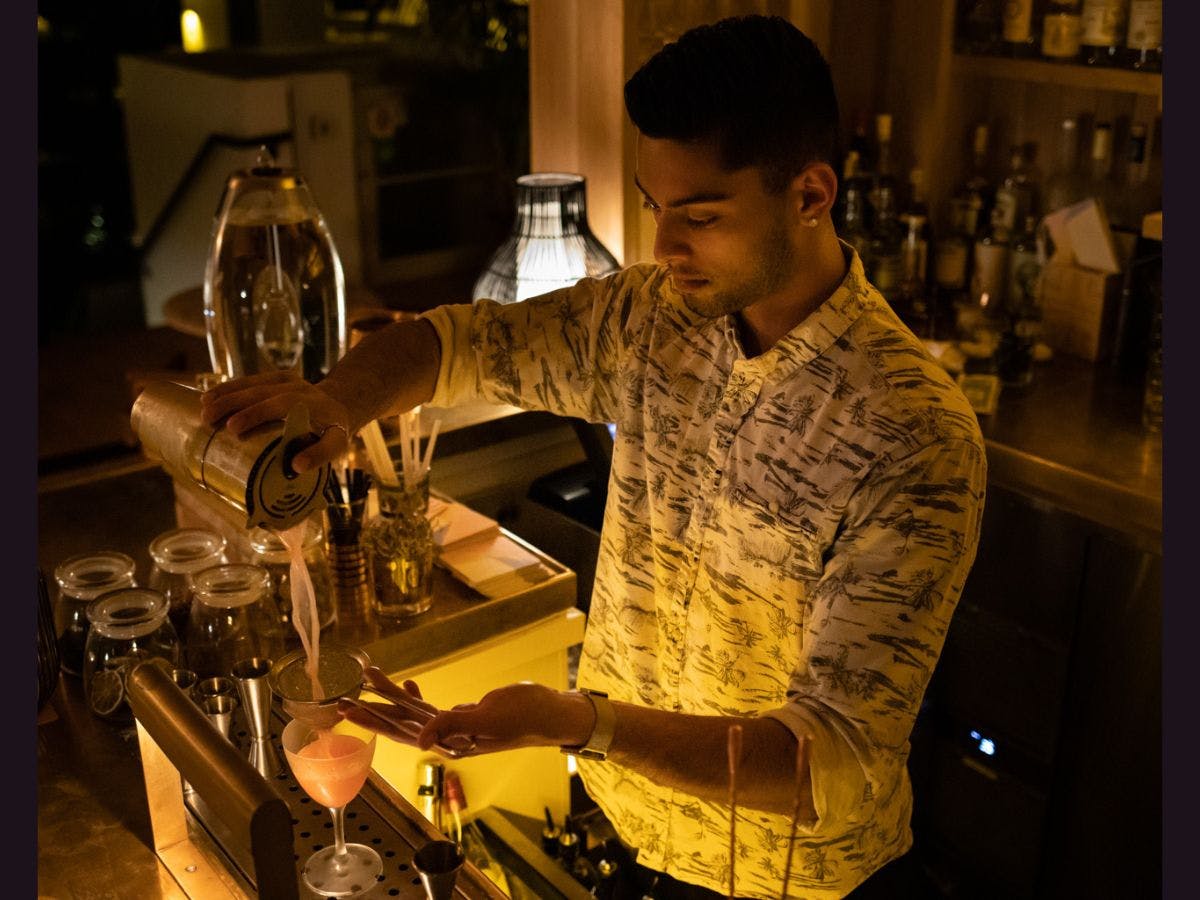 Man bartending pouring drinks in an environmental portrait.