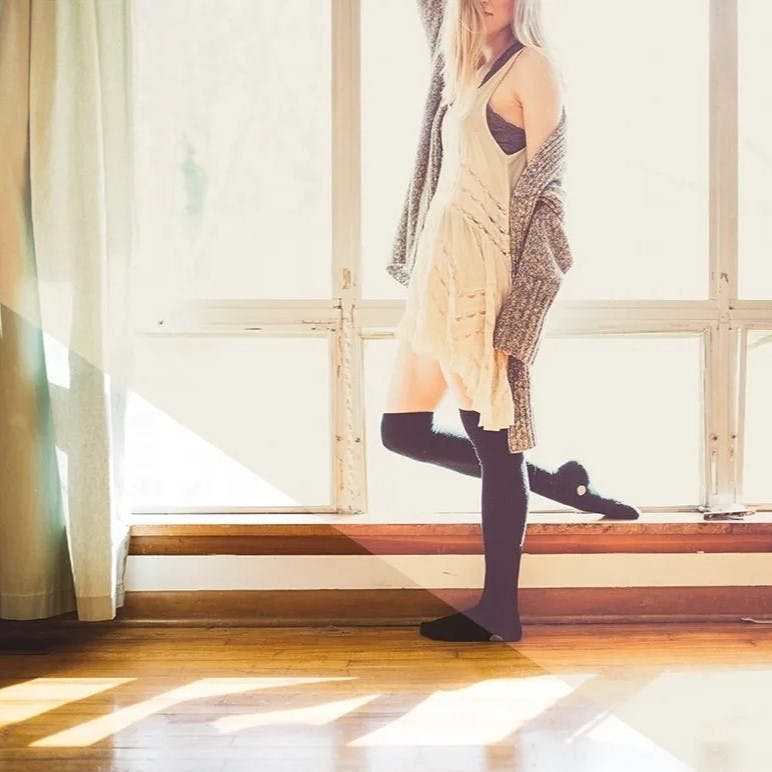 Woman with long black socks on hard wood floor.