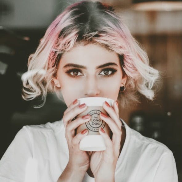 Pink hair girl sipping coffee.