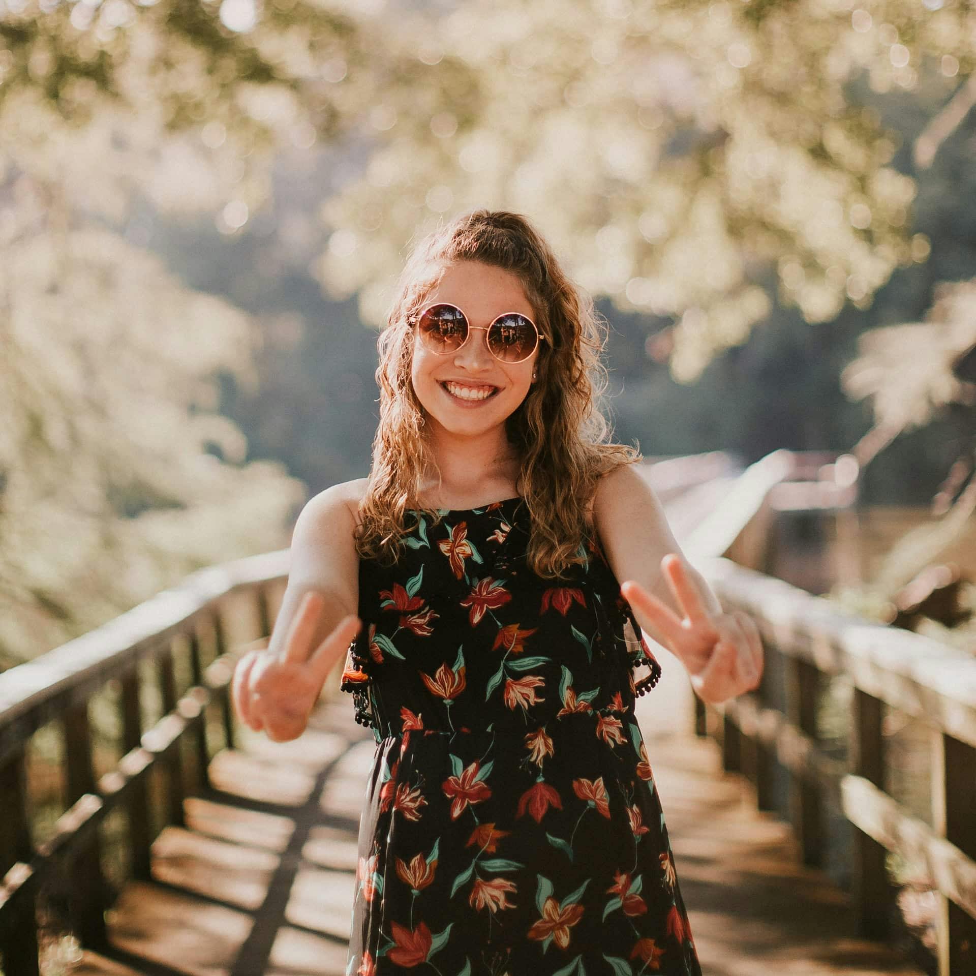 Girl giving two peace signs while standing on bridge.