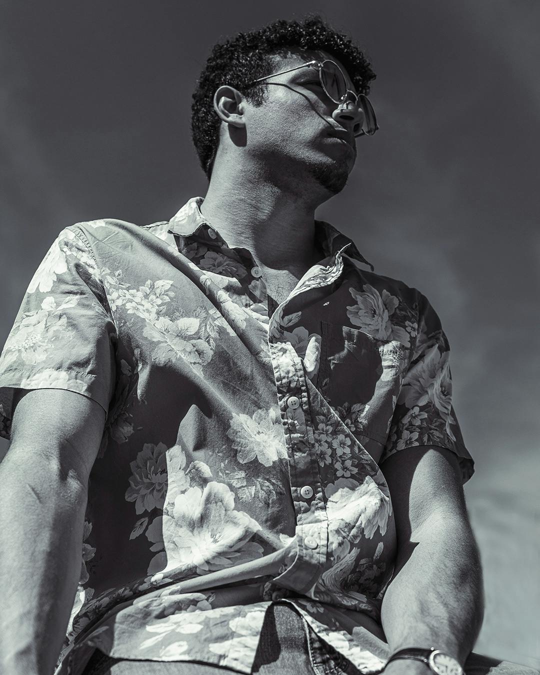 Black and white photo of man in flower shirt during hard light.