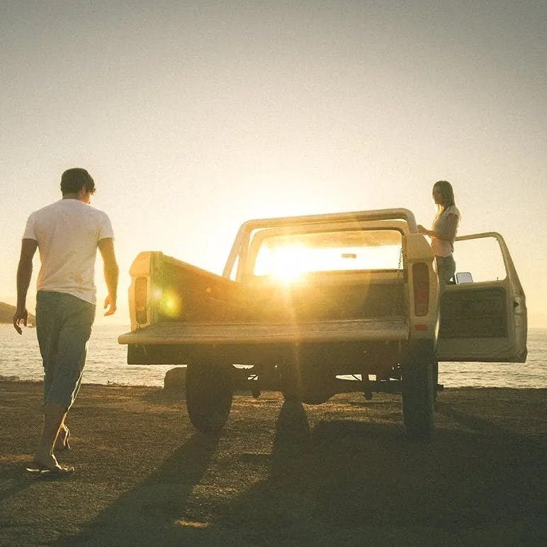 Guy and girl with car on the beach.