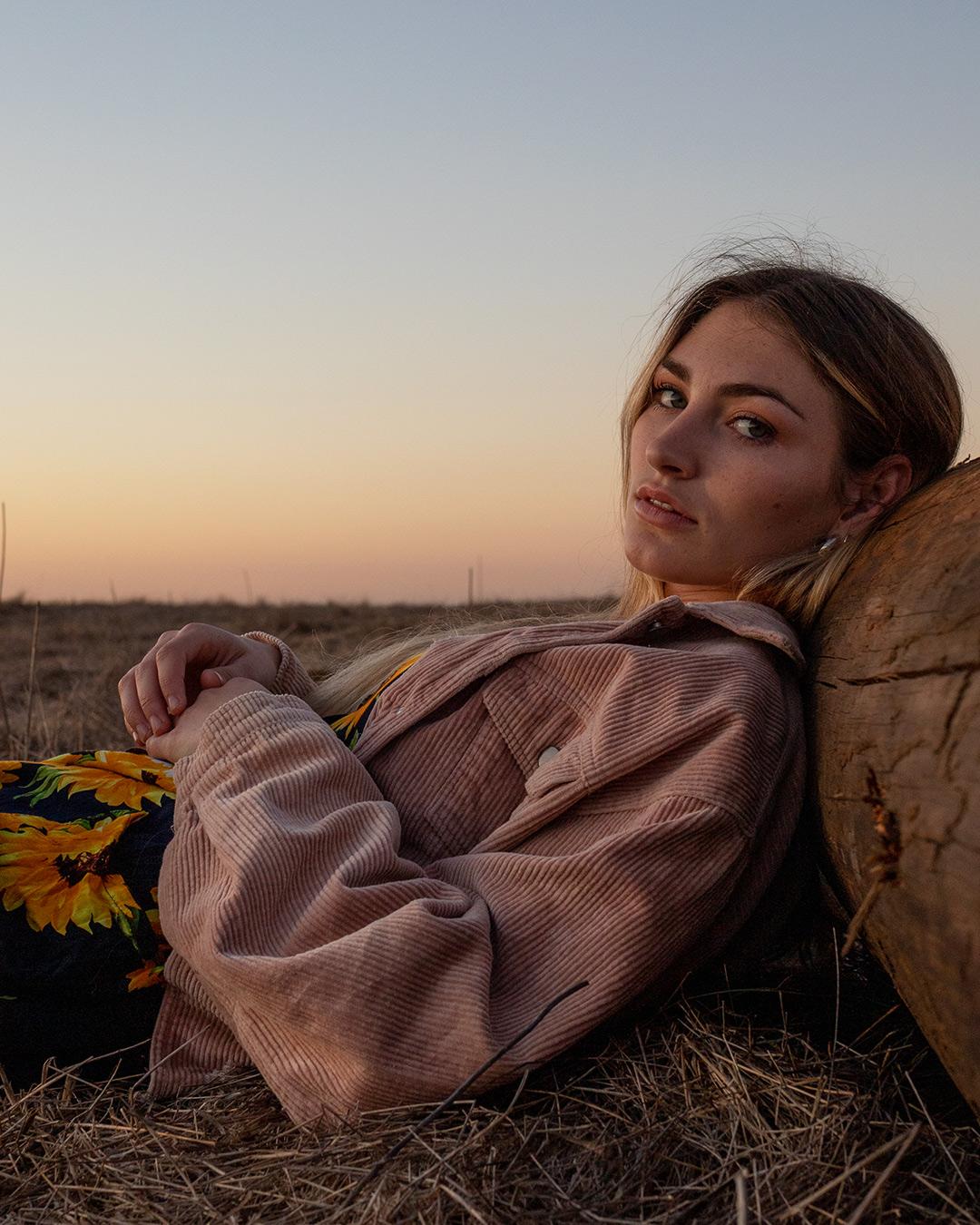 Woman leaning against wooden log.