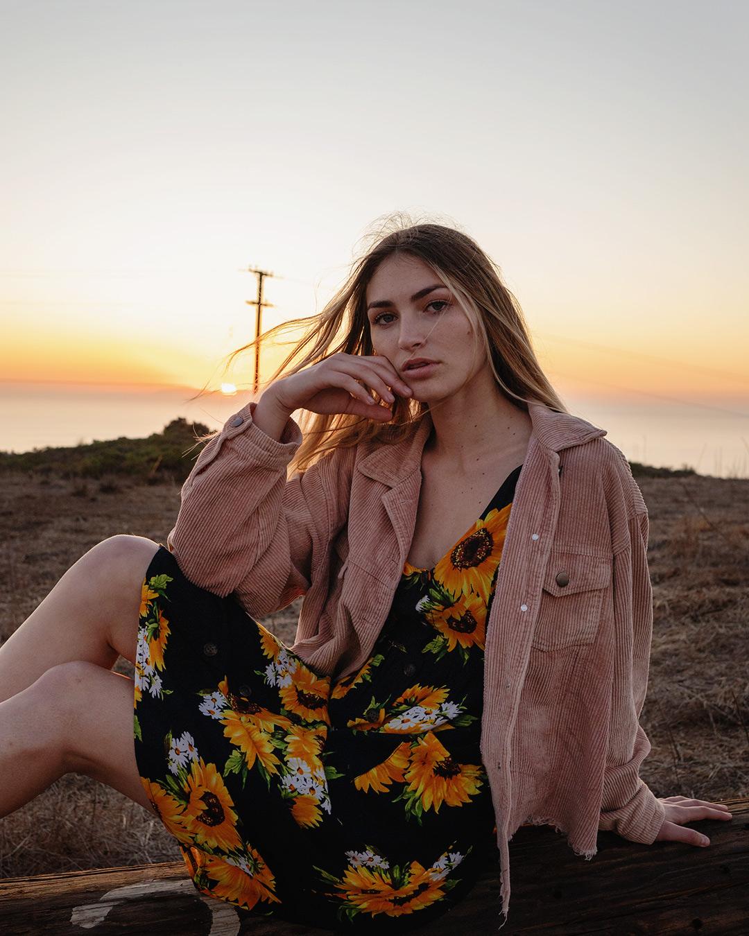 Woman sitting on a log with her legs sideways.