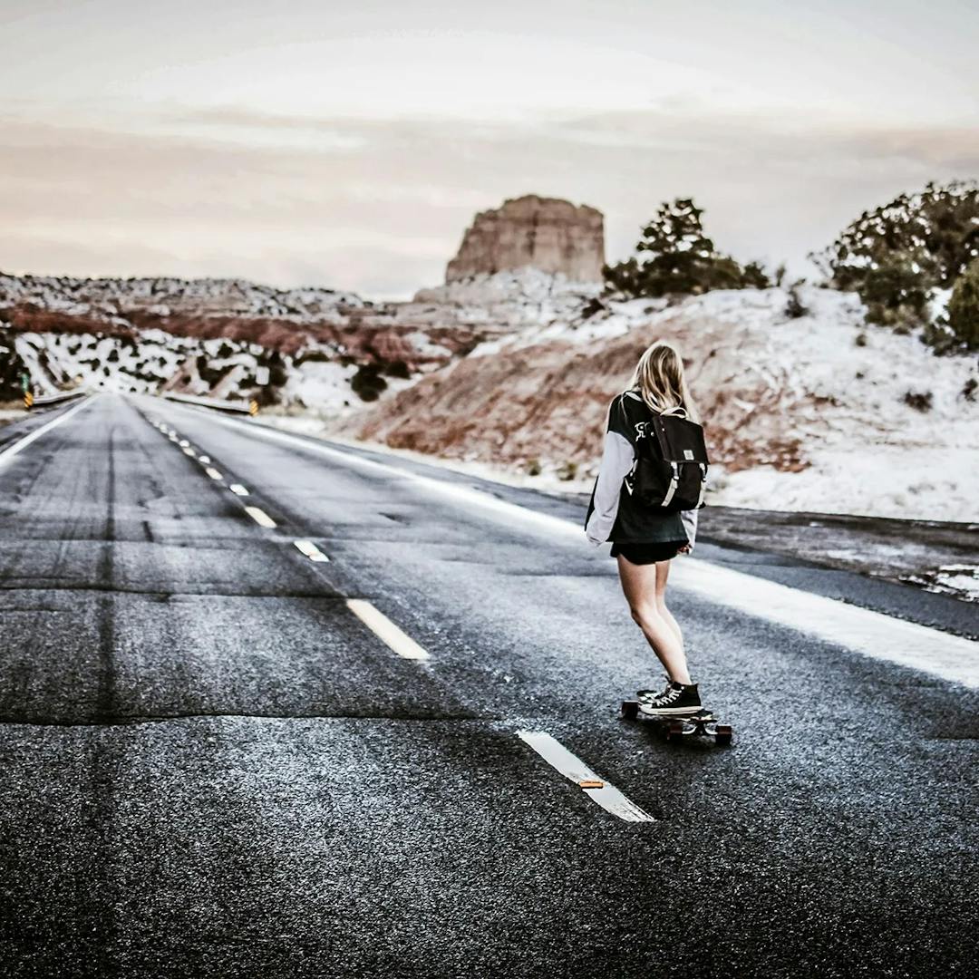 Woman skateboarding down empty street.