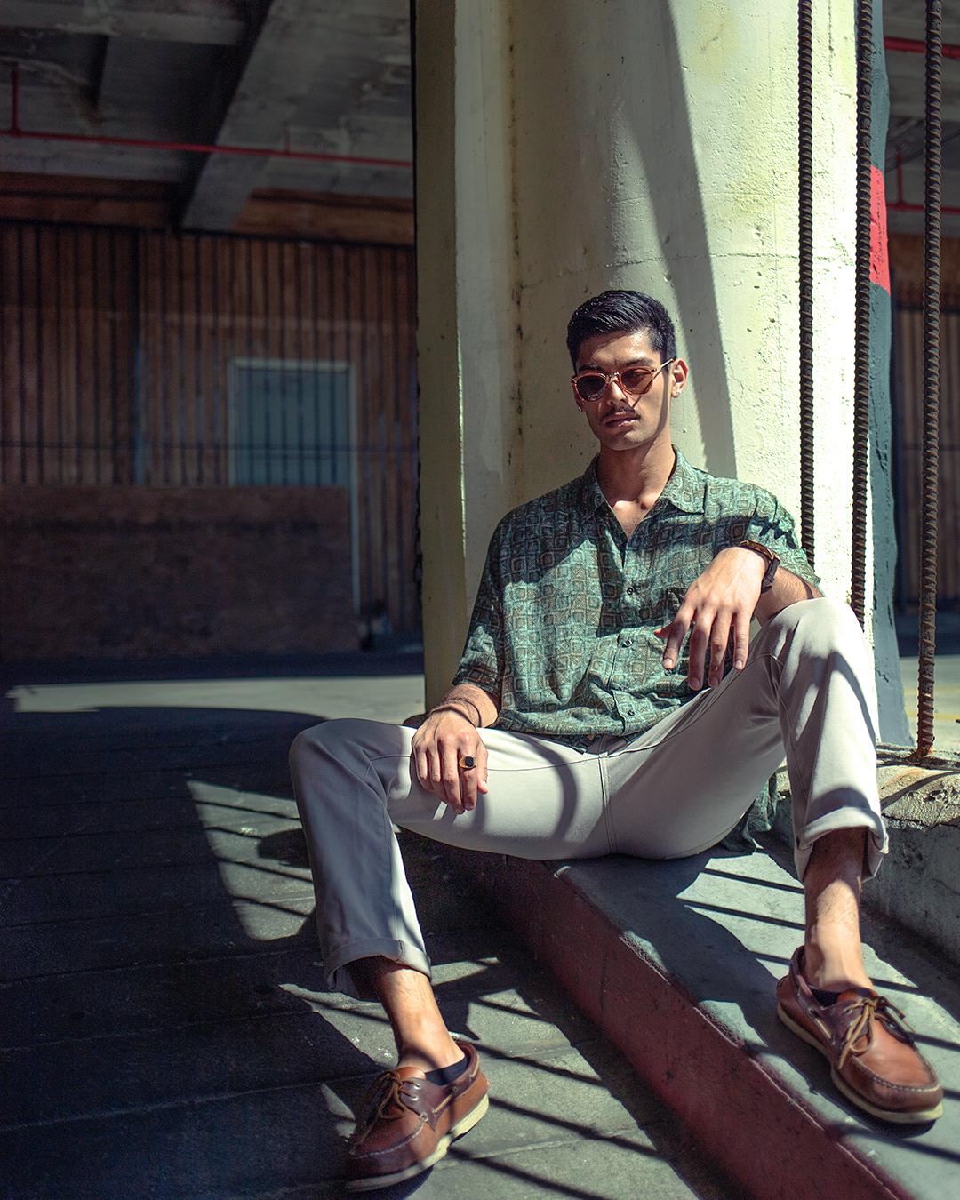 Man sitting leaning against a wall with bent legs.