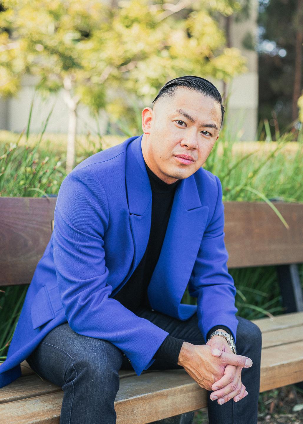 Man sitting on bench with arms on elbows 45 degrees from the camera.