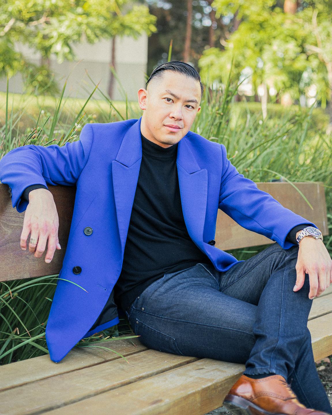 Man sitting on a bench with legs crossed over partially.