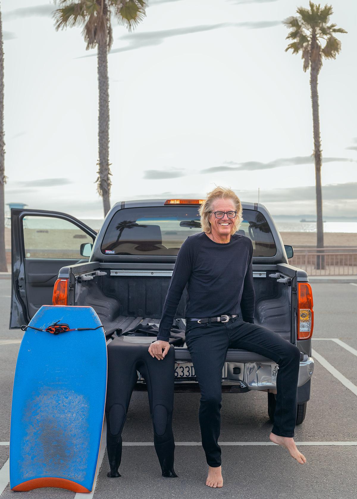 Man sitting on his truck with his legs dangling.