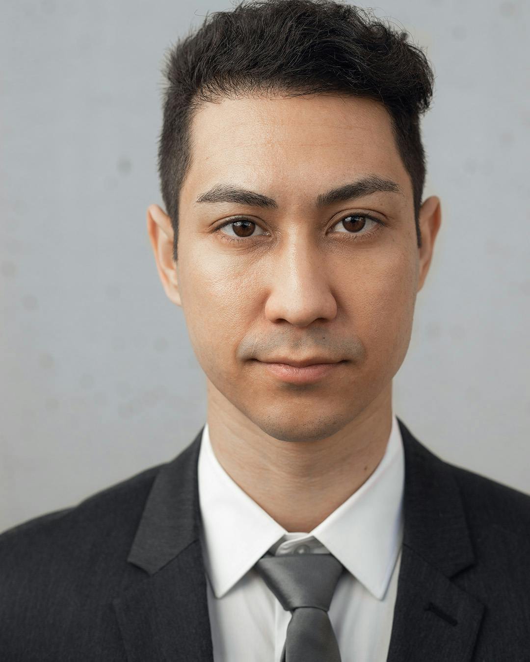 Man wearing solid black color suit for his headshot.