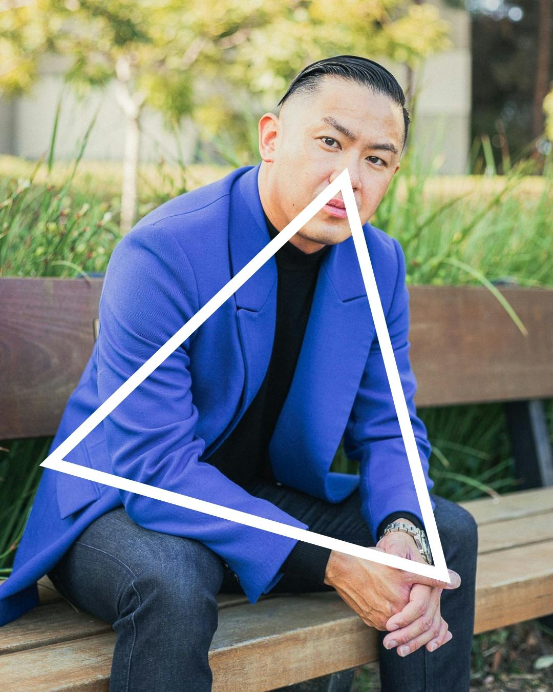 Man in blue suit sitting on bench in a triangle pose.