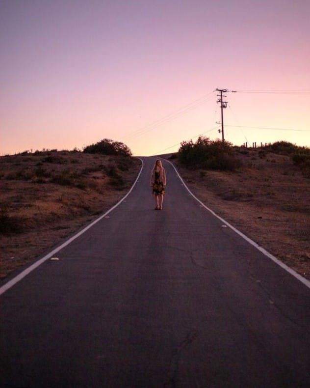 Woman standing in the middle of the road creating negative space with leading lines.