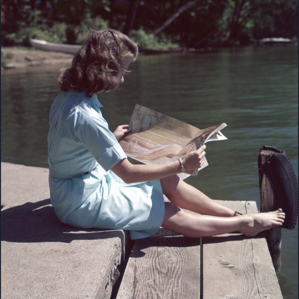 Woman reading newspaper on boat dock.