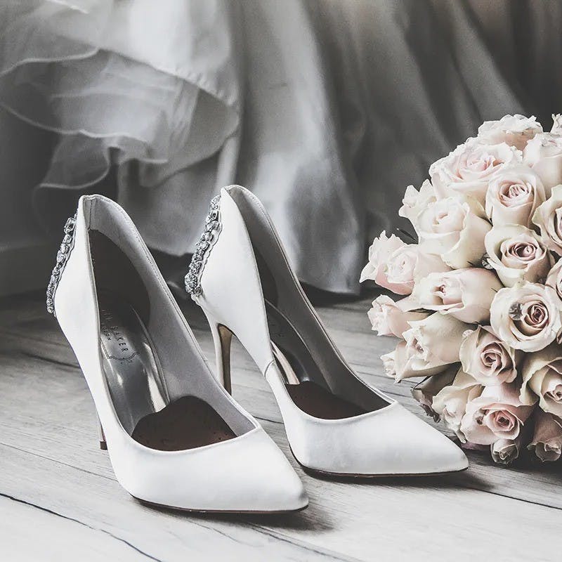 Wedding dress shoes on floor with flowers.